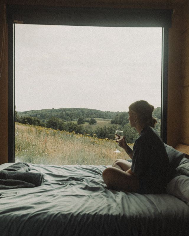 Inside a HIDE n SEEK cabin, a bed looking out to the fields
